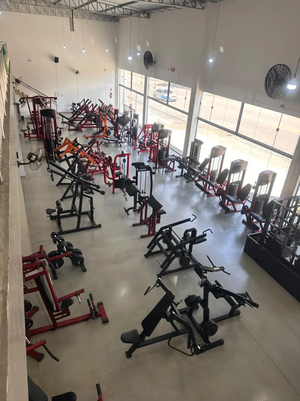Vista de cima do salão da Olimpo Atena, com máquinas de musculação em linha e luz natural
